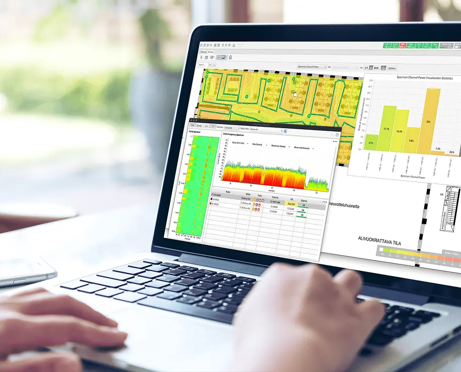 A person using a laptop that displays graphs and data analysis related to some form of monitoring or measurement.