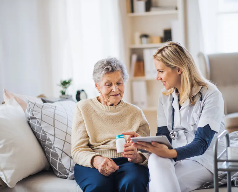 A healthcare professional sitting with an elderly woman