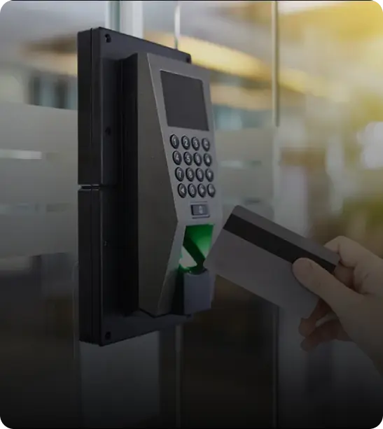 A hand inserting a card into a card reader mounted on a wall.