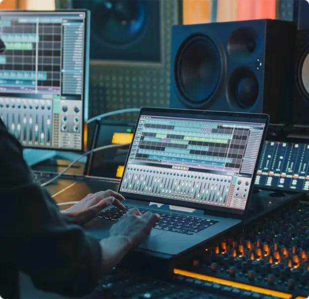 A person working on a laptop in a music production studio