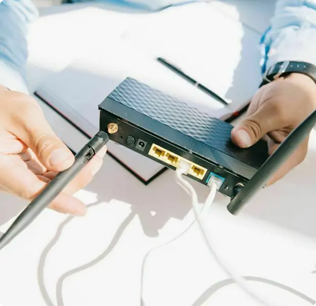 A person holding a device with multiple ports and antennas, connecting cables to it.