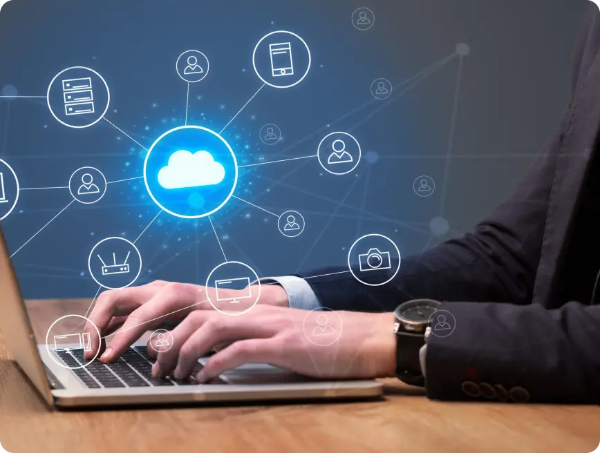 A person typing on a laptop with cloud computing icons and networking symbols displayed around.