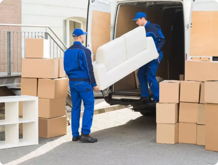 Two men in blue uniforms are moving furniture out of a moving van