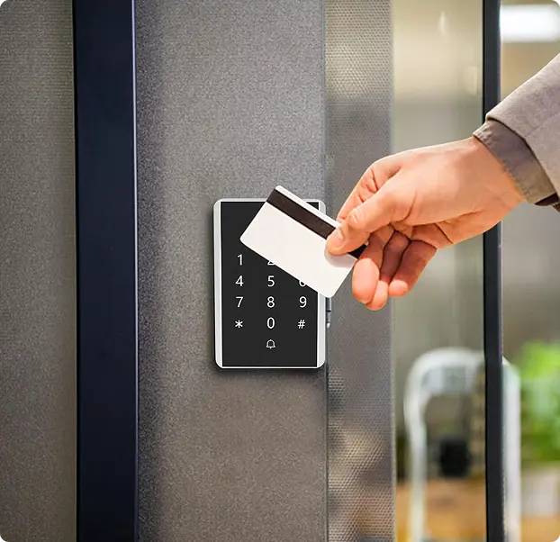 A person using a card to unlock a keypad entry system.