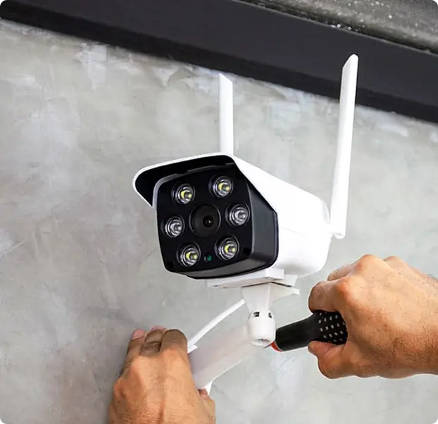A person installing a security camera on a wall.