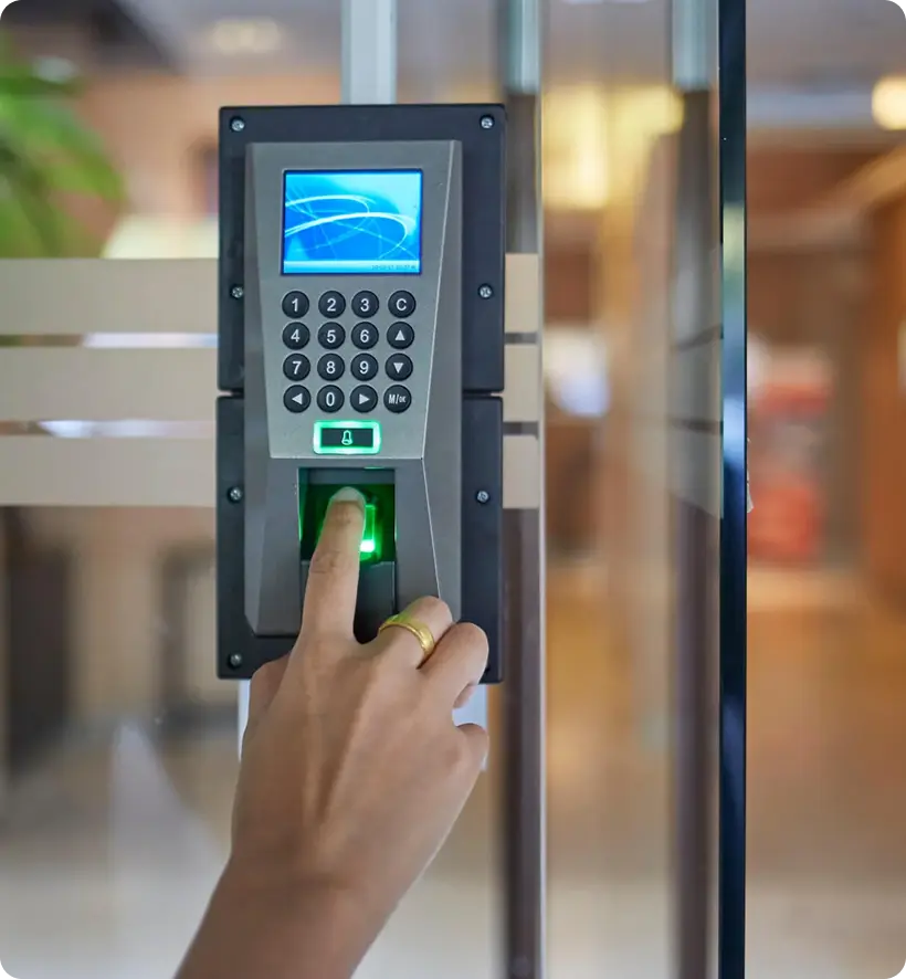 A hand is using a fingerprint scanner on a digital access control panel, with a keypad and a display screen.