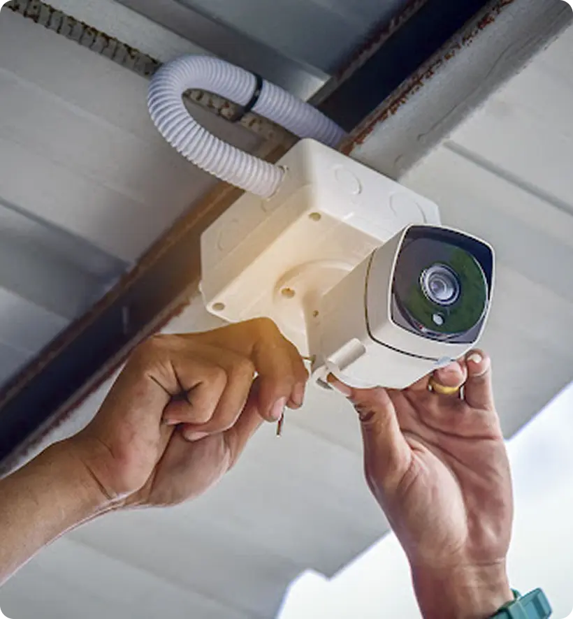 A person installing a security camera on a ceiling.