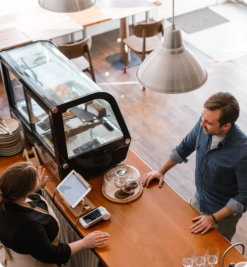 A man and a woman are interacting at a café,