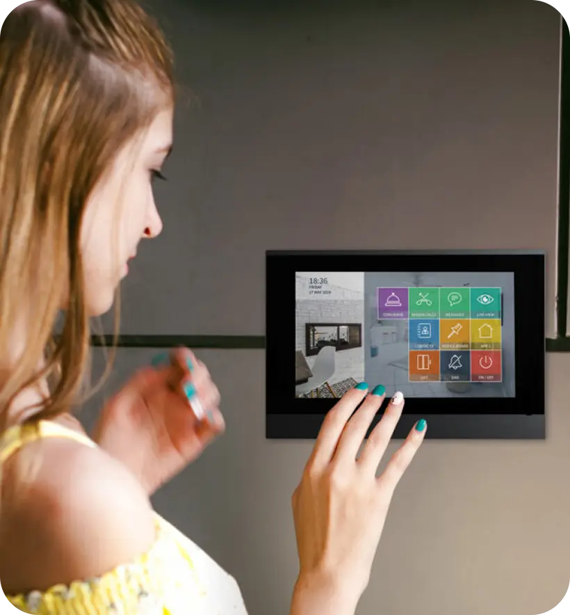 A girl interacting with a touchscreen control panel mounted on a wall.